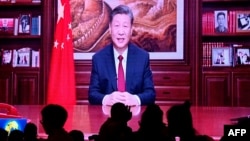 2023 年 12 月 31 日，人们在一家餐厅吃晚饭，屏幕上播放着中国国家主席习近平在北京发表新年讲话的画面。(法新社)