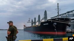 FILE - A security officer stands next to the ship Navi-Star loaded with grain as it waits to sail to sail from the Odesa Sea Port, in Odesa, Ukraine, on July 29, 2022.