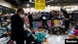 ARCHIVO - Clientes compran en una zapatería durante una venta de liquidación en un centro comercial en Beijing, China, el 15 de enero de 2023.