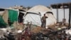 People stand in the midst of the destruction in the aftermath of a reported overnight Israeli strike that hit tents used as temporary shelters by displaced Palestinians in Deir el-Balah, central Gaza Strip, on August 4, 2024.