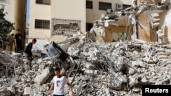 Anak-anak Palestina berjalan di tengah puing-puing bangunan yang rusak akibat serangan Israel di kamp Jenin di Tepi Barat yang diduduki Israel, 23 Mei 2024. (REUTERS /Raneen Sawafta)