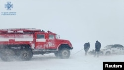 Petugas melepaskan mobil yang terjebak salju saat badai salju melanda wilayah Odesa, Ukraina, dalam gambar selebaran yang dirilis 27 November 2023. (Layanan pers Layanan Darurat Negara Ukraina di wilayah Odesa/Handout via REUTERS)