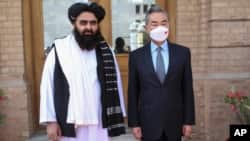FILE - In this photo released by Xinhua News Agency, Chinese Foreign Minister Wang Yi poses for photos with Amir Khan Muttaqi, acting foreign minister of the Afghan Taliban's caretaker government, in Kabul, March 24, 2022. (Saifurahman Safi/Xinhua via AP)