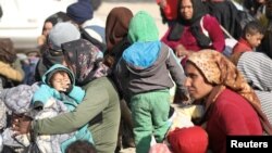 Displaced women who fled the Aleppo countryside sit with their children in Tabqa, Syria, Dec. 4, 2024.