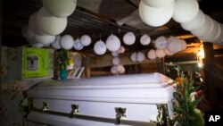 Balon-balon tergantung di atas peti mati jenazah seorang anak perempuan berusia 7 tahun, Jakelin Caal Maquin, di rumah kakeknya di San Antonio Secortez, Guatemala, Senin, 24 Desember 2018 (foto: AP Photo/Oliver de Ros)