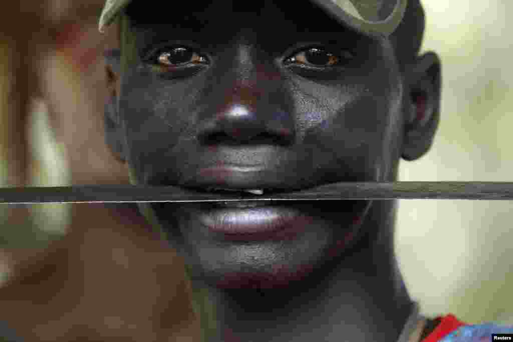 Un combattant de la milice chrétienne anti-balaka tient une machette entre ses dents à l’état-major de son mouvement dans la bourgade de Boeing du Nord de Bangui, une zone près de l’aéroport international de Boeing. Le 22 février 2014.