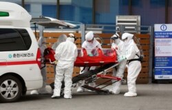 A confirmed coronavirus patient is wheeled to a hospital at Chuncheon, South Korea, Feb. 22, 2020.