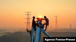 Employees work on a high voltage transmission tower in Yichun, in China's central Jiangxi province, Sept. 28, 2021.