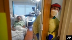 Registered nurse Rachel Chamberlin steps out of an isolation room where where Fred Rutherford recovers from COVID-19 at Dartmouth-Hitchcock Medical Center, in Lebanon, NH, Jan. 3, 2022.