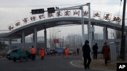 资料照：中国新疆和田居民走过“和田市纺织服装实训就业基地”的工厂大门。（2019年10月1日）