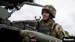 Український військовослужбовець 55-ї окремої артилерійської бригади несе снаряд для самохідної гаубиці "Цезарь" поблизу міста Авдіївка Донецької області, 31 травня 2023 року. (Фото: REUTERS/ В'ячеслав Ратинський)