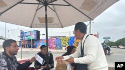Hugo López, del grupo defensor Al Otro Lado, entrega un volante a Antonio Cortes, un mexicano deportado de Estados Unidos a Tijuana, México, el 11 de junio de 2024.