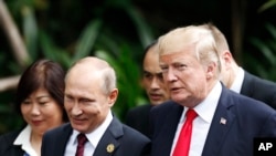 FILE - U.S. President Donald Trump, right, and Russia's President Vladimir Putin, center, talk during a group photo session at the APEC Summit in Danang, Nov. 11, 2017.
