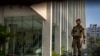 FILE - An armed security person stands guard at the gate of a building housing BBC office in New Delhi, India, on Feb. 15, 2023. Indian police raided the offices of a news website and homes of journalists, in what critics described as an attack on an independent news outlet.