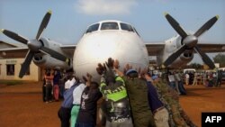 Des responsables de la MONUC et des volontaires congolais poussent un avion de l'ONU le 25 juillet 2002