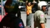 A Cambodian lawmaker from the main opposition party of Cambodia National Rescue Party (CNRP) Mu Sochua, center, gestures to make the number seven, the party's ballot number, before being detained by authorities at Freedom Park, in Phnom Penh, Cambodia, Tuesday, July 15, 2014. Three lawmakers from the opposition CNRP were detained and sent to police headquarters for leading about a hundred of their supporters to demonstrate in front of the park, asking authorities to open the site to the public. (AP Photo/Heng Sinith)