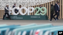 與會者走過會場外的COP29聯合國氣候高峰會標誌。 (美聯社：2024年11月23日)