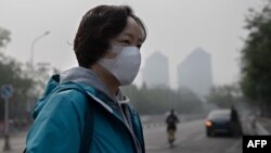 A woman wears a protective mask to fight bad air pollution in Beijing on October 22, 2018. (Photo by Nicolas ASFOURI / AFP)
