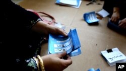 FILE - An Afghan election worker counts ballots at a polling station in Jalalabad, east of Kabul, Afghanistan, June 14, 2014. 