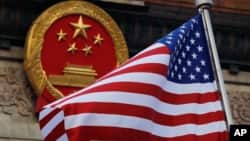 FILE - An American flag is flown next to the Chinese national emblem.