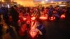 Personas encienden velas y dejan flores en un altar improvisado ubicado frente a la sala de conciertos Crocus City Hall, el domingo 24 de marzo de 2024, a las afueras de Moscú. 