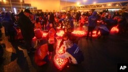 Personas encienden velas y dejan flores en un altar improvisado ubicado frente a la sala de conciertos Crocus City Hall, el domingo 24 de marzo de 2024, a las afueras de Moscú. 