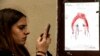 A woman checks her smartphone by a poster showing a weeping image of Marianne, symbol of the French Republic, near Le Carillon restaurant, a site of terrorist attacks, in Paris, Nov. 17, 2015. The attacks have triggered waves of social media communication