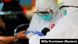 Petugas kesehatan mengenakan alat pelindung mengambil sampel darah untuk menguji seorang pria terhadap virus corona (COVID-19) di Bogor, Jawa Barat, 7 April 2020. (Foto: Reuters/Willy Kurniawan)
