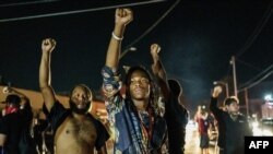 Protesters raise their fists during a demonstration against the shooting of Jacob Blake in Kenosha, Wisconsin on August 26, 2020. - Two people were shot dead and a third injured on the night of August 25 in the US city of Kenosha, Wisconsin.