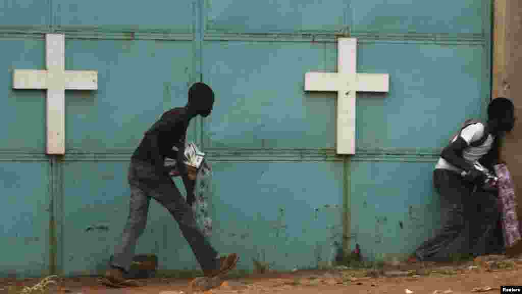 Des passants essaient de s’abritent près d’une église au cours des combats entre les soldats africains de maintien de paix et les combattants de la milice chrétienne anti-balaka, Bangui, le 18 février 2014.