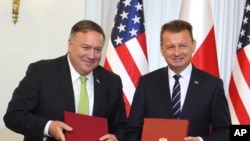 Državni sekretar SAD Majk Pompeo (levo) i poljski ministar odbrane Marius Blaščak poziraju reporterima nakon potpisivanja amerčko-poljksog Unapređenog sporazuma o odbrabenoj saradnji, u Predsedničkoj palati u Vašravi, Poljska, 15. avgusta 2020.