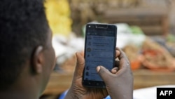 Une femme passe en revue son compte WhatsApp sur son téléphone, à Kampala, le 5 juillet 2018.