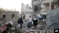 FILE - People inspect the damage of houses destroyed by Saudi-led airstrikes in Sanaa, Yemen, June. 9, 2017. 